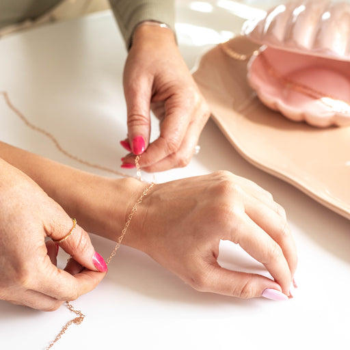 Person placing the heart chain ella on top of a woman's wrist