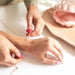 Person placing the heart chain ella on top of a woman's wrist