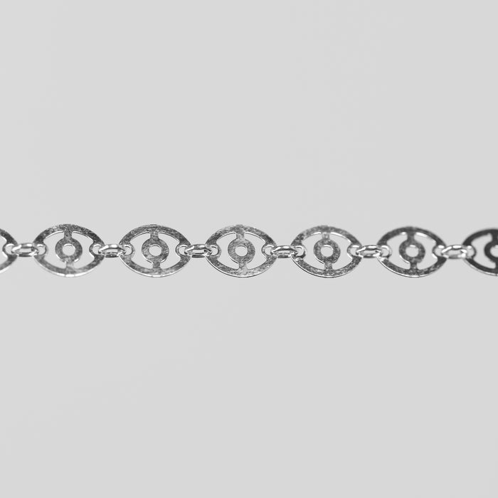 Closeup shot of the claire silver chain with disks linked together over a light gray background