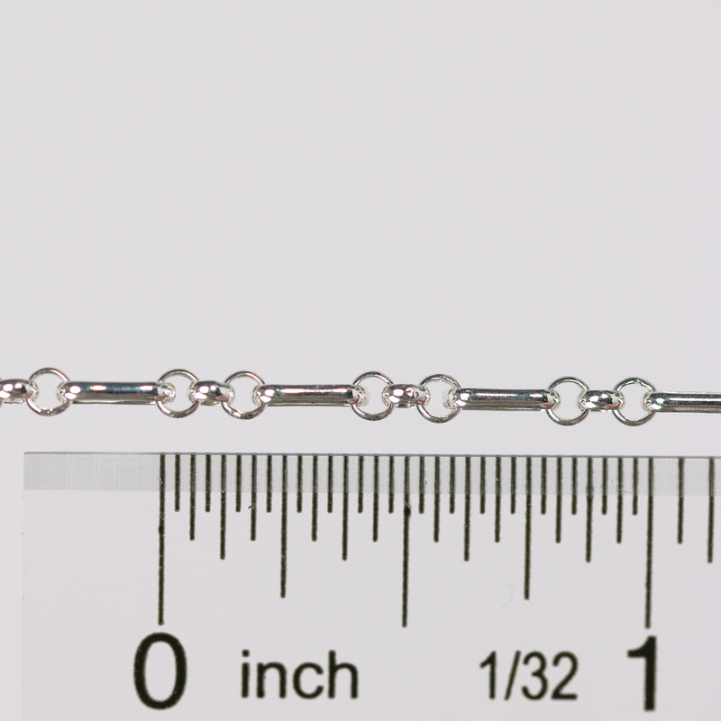 Silver rolo chain with a ruler for scale on a white background