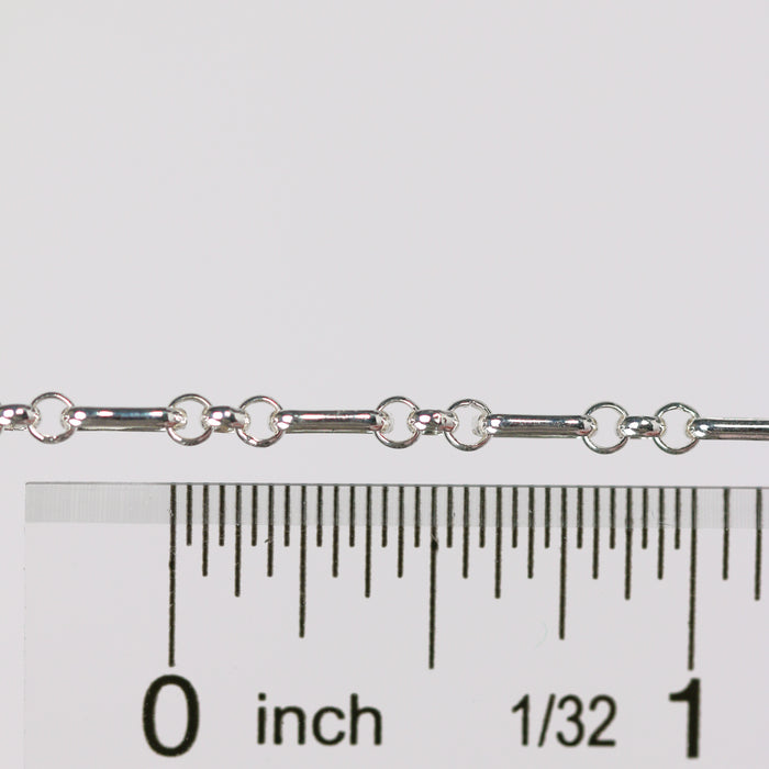 Silver rolo chain with a ruler for scale on a white background