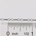 Silver rolo chain with a ruler for scale on a white background