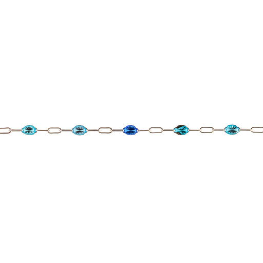 A delicate permanent jewelry chain featuring oval and elongated links, interspersed with enamel beads in shades of light blue, royal blue, and turquoise with dark inclusions, shown against a plain white background.