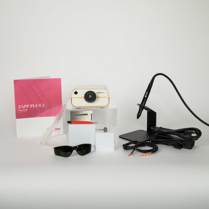Welder, safety glasses, and accessories on a white surface with a pink Zapp Plus 2 manual.