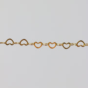Yellow gold chain with heart-shaped links on a light gray background