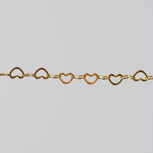 Yellow gold chain with heart-shaped links on a light gray background