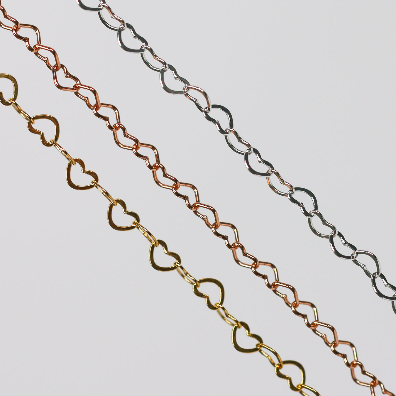 Three chains made from heart links in Yellow Gold, Rose Gold, and Sterling Silver