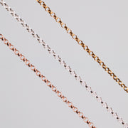 Three round linked permanent jewelry chains in different metal types and colors showcased on a light background.