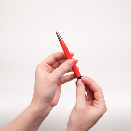 Red fiberglass brush being held by two hands diagonally in the air