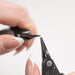 Close-up of a person using a pair of black micro precision pliers on a white background