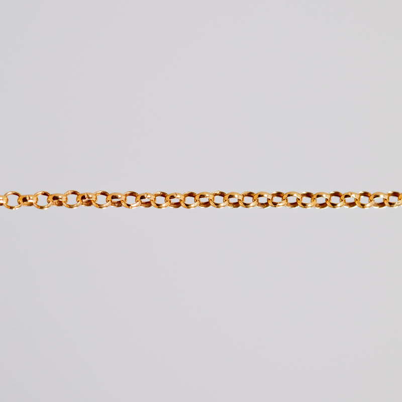 Yellow gold filled rolo chain for permanent jewelry being shown pulled tight across a light background.
