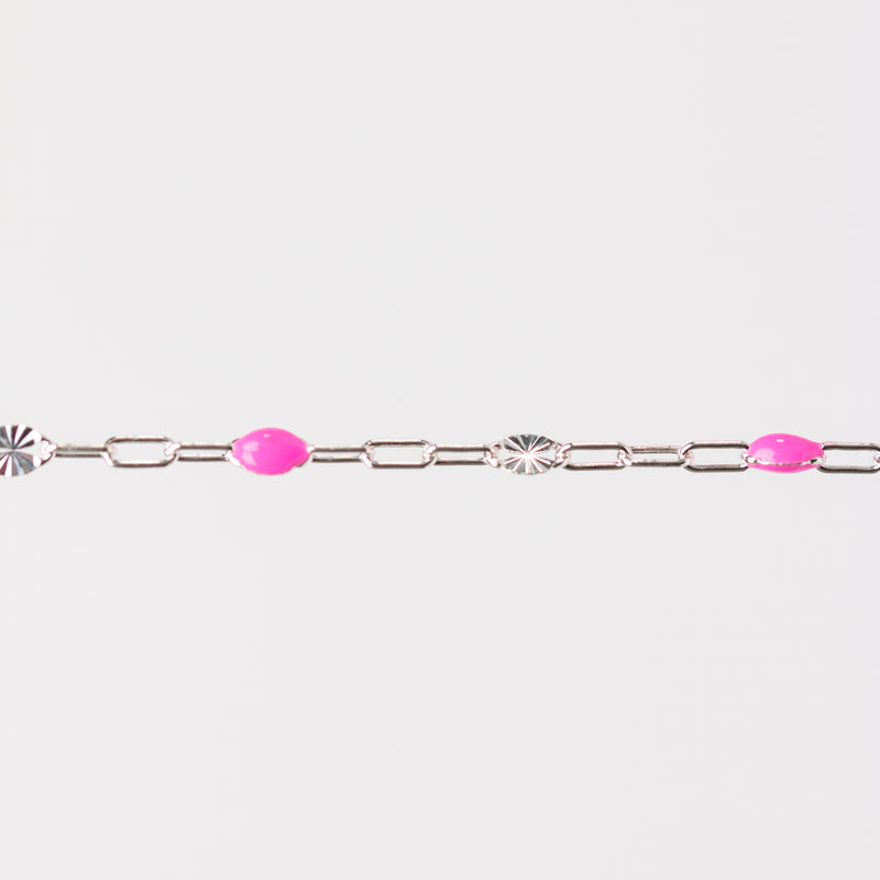 Silver bracelet with pink enamel beads and starburst links on a white background
