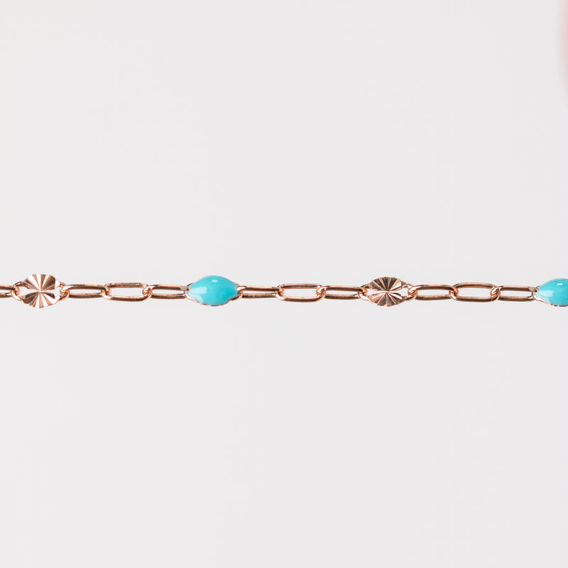 Rose gold chain bracelet with turquoise beads made from enamel on a white background