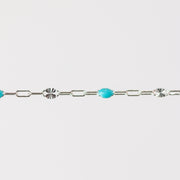 Silver chain bracelet with turquoise beads made from enamel on a light gray background