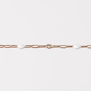 Rose gold chain bracelet on a light gray background with white enamel
