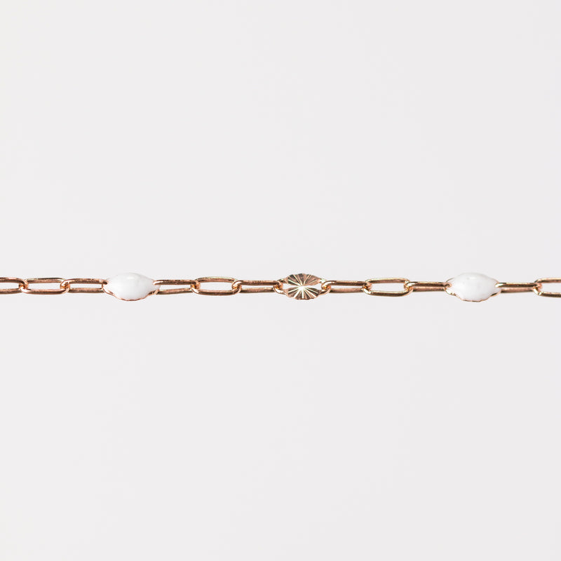 Rose gold chain bracelet on a light gray background with white enamel