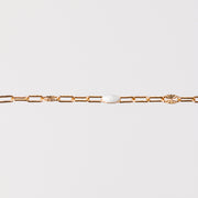 Yellow gold chain bracelet with a white enamel on a light gray background