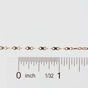 Gold chain next to a ruler on a white background