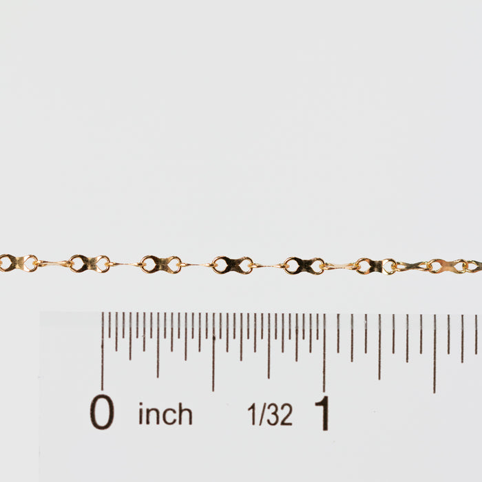Gold chain next to a ruler on a white background