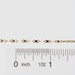 Gold chain next to a ruler on a white background