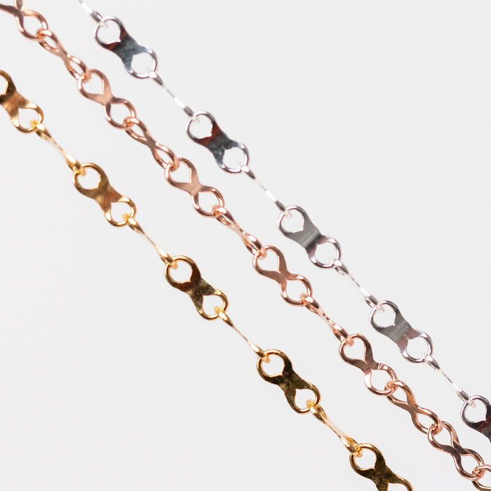 Three chains of different metal types on a light gray background