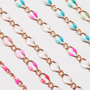 A photo with 6 chains. One chain has hot pink enamel beads. One is alternating soft pink, hot pink, pinky red, and white. One chain is all white. One chain is alternating blue, pink white. One chain is all blue. One chain is alternating blues and greens.