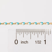 Chain is being held next to a ruler with inches as the measurement. The chain is gold filled yellow with blue enamel beading.
