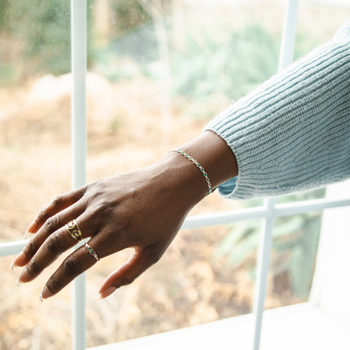 Model is wearing the blue enamel silver link bracelet in front of a window with her hand held out.