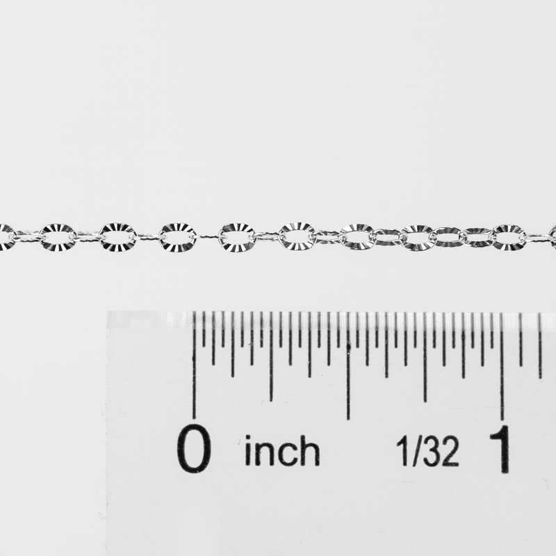 Silver textured oval links up against a ruler to help with meaurements and length.