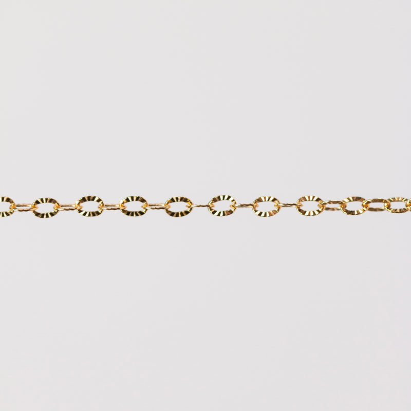 Shiny textured oval links reflecting yellow gold. Hammered starburst pattern.