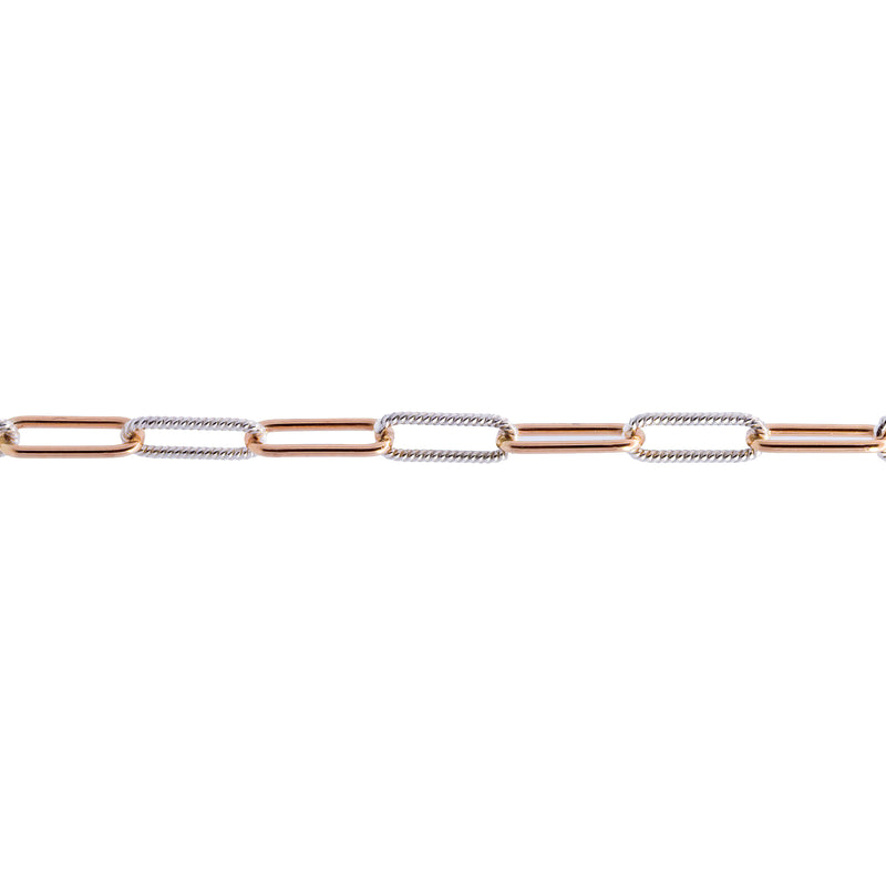 A close-up of a mixed metal chain for permanent jewelry featuring alternating yellow gold and silver paperclip-style links on a plain white background.