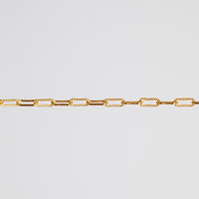 A close-up of a gold chain featuring alternating smooth oval links and twisted rope-style oval links, set against a solid light gray background.