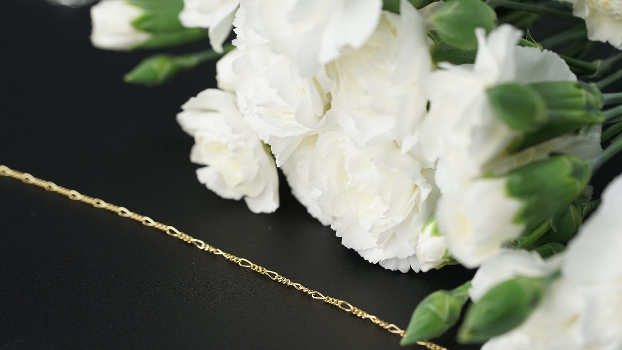 Chain laying next to white flowers on a black background