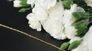 Chain laying next to white flowers on a black background