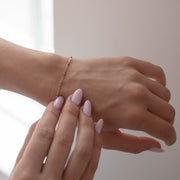 Woman holding a permanent jewelry enamel bracelet chain on her wrist