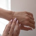 Woman holding a permanent jewelry enamel bracelet chain on her wrist