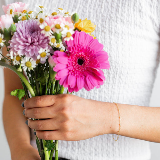 Woman holding flowers while wearing a beaded cable bracelet chain on her wrist