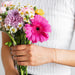 Woman holding flowers while wearing a beaded cable bracelet chain on her wrist