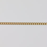 Gold curb chain laying flat on a gray background