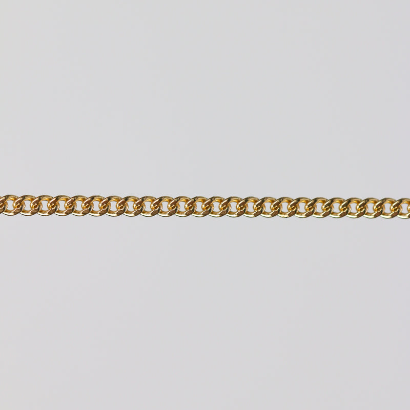 Gold curb chain laying flat on a gray background