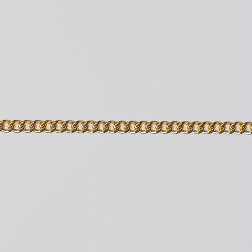 Gold curb chain laying flat on a gray background