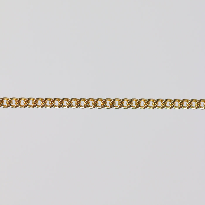 Gold curb chain laying flat on a gray background