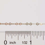 Gold chain with a ruler for scale on a white background