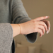 Close-up of a person's wrist wearing a gold bracelet against a neutral background