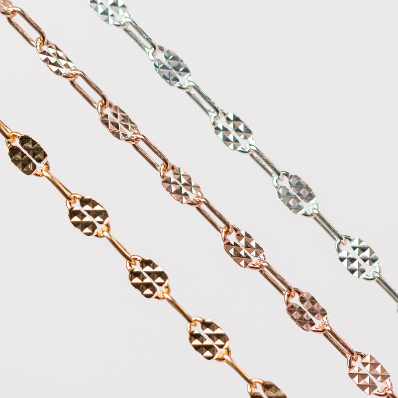 Three chains of different metal types on a light gray background