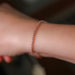 A closeup photo of a rose gold rolo chain on a woman's wrist showing the chain links