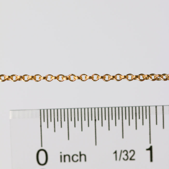 Gold chain next to a ruler on a white background