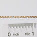 Gold chain next to a ruler on a white background