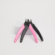 Pair of pink and black pliers for precision on a white background