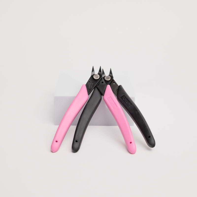 Pair of pink and black pliers for precision on a white background